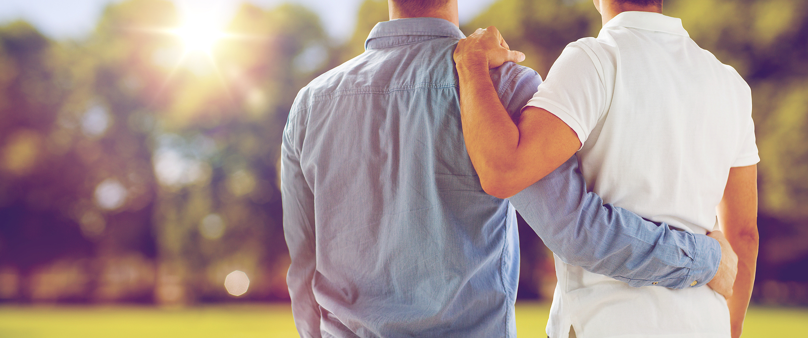 couple or friends hugging from back over natural outdoor background